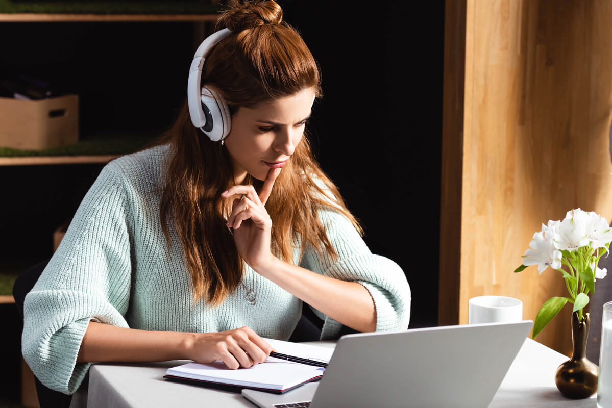 Young female student studying remotely on her computer in a coffee shop